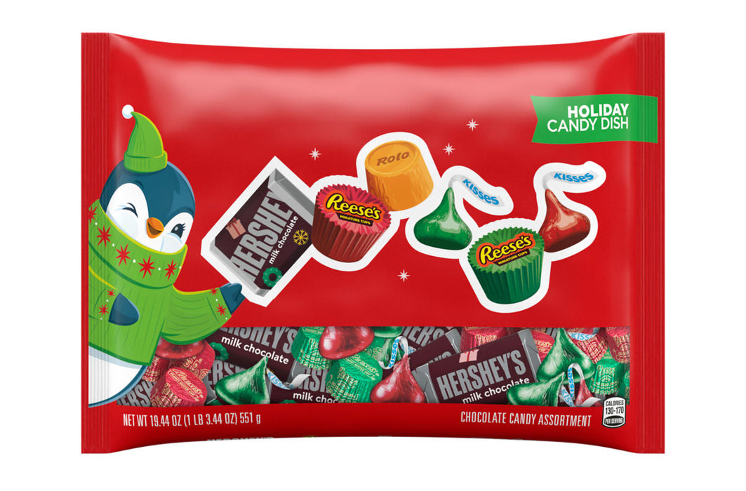 A red bag of holiday candy assortment featuring Hershey's and Reese's chocolate candies, with a penguin character and a green 'Holiday Candy Dish' label on a white background.
