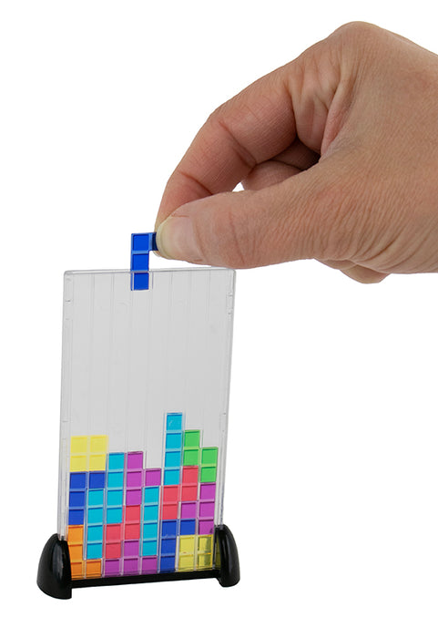 Hand holding a small transparent stand with colorful block design on a white background
