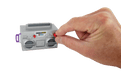 Hand holding a small gray toy boombox against a beige background