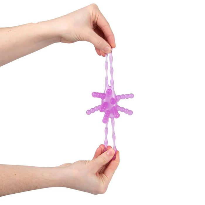 A person's hands holding a translucent purple star-shaped silicone toy with textured, beaded arms against a plain white background.
