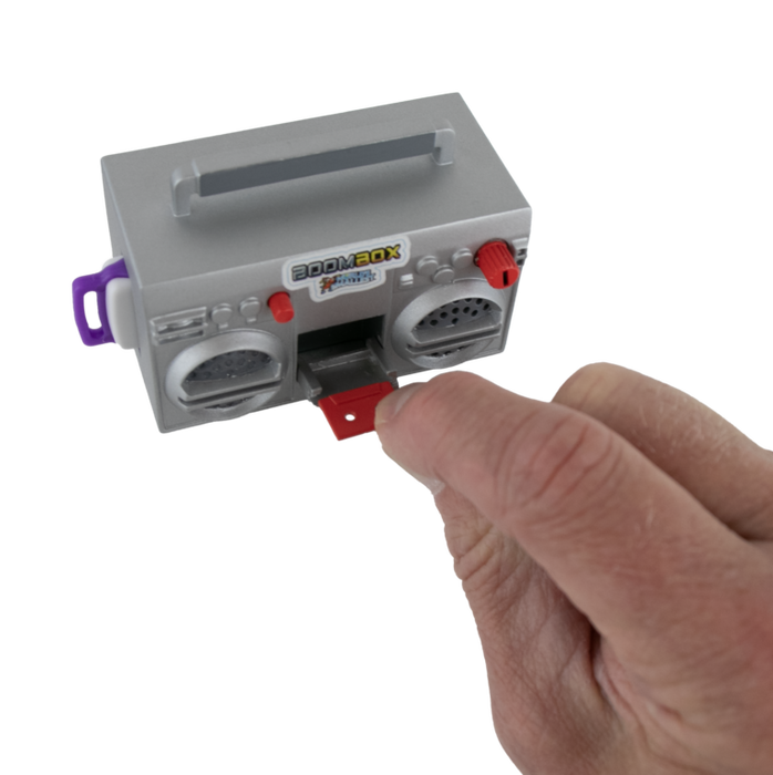 Small gray boombox toy held by a hand on a white background