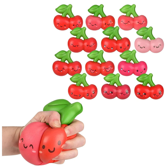 A set of cherry-shaped squishy stress toys with cute cartoon faces, shown with one being squeezed by a hand on a white background.