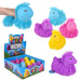 A set of colorful, fuzzy puffer unicorn toys shown on a white background, including a large blue one being held by a hand, several smaller puffer toys in purple, pink, and yellow, a retail display box, and a small brand tag. The brand 'Shaggy Puffer Unicorns' is visible on the packaging.