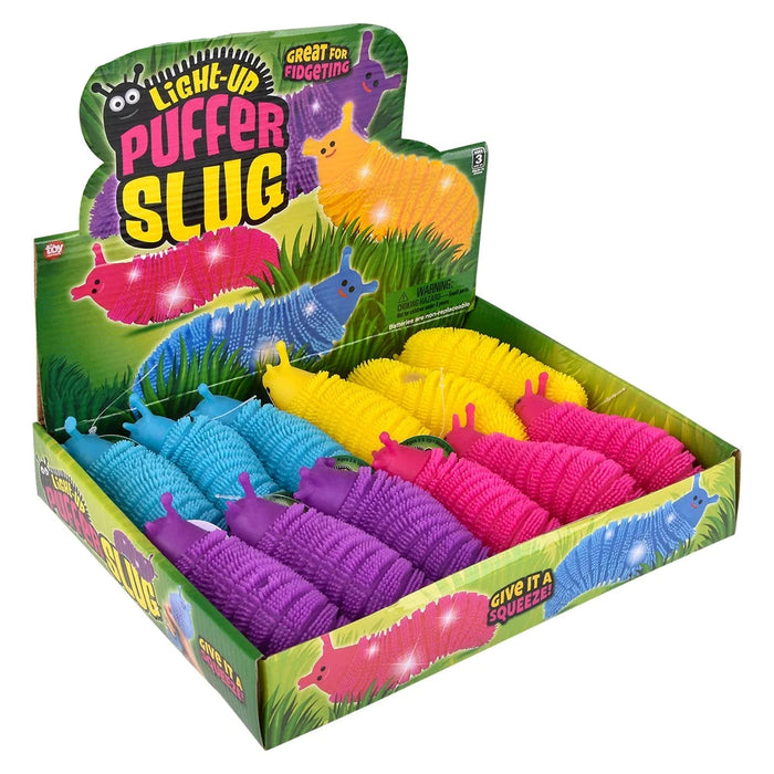 A retail display box filled with colorful puffer slug toys. The display features a green illustrated backing card with the text 'LIGHE-UP PUFFER SLUG' and shows multiple plastic slug toys in pink, blue, yellow, purple, and orange arranged in rows inside the box.