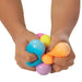 Colorful stress balls being squeezed by a child's hands on a white background