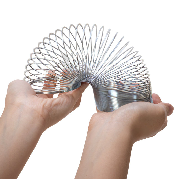 Metallic spring toy held by hands on a white background