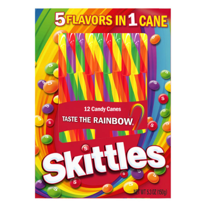 A box of Skittles candy canes featuring a bright rainbow design with the words '5 FLAVORS IN 1 CANE' and 'TASTE THE RAINBOW.' The Skittles logo is large at the bottom, and candy-coated sticks are shown through a clear window on the front.