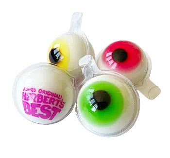 Four novelty gummy eyeballs in clear plastic clamshell packaging on a white background. Two gummies have yellow and red outer rims, and two have green outer rims.