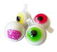 Four novelty gummy eyeballs in clear plastic clamshell packaging on a white background. Two gummies have yellow and red outer rims, and two have green outer rims.